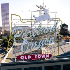 cityscape with a high rise in the background and the White Stag Portland Oregon Old Town sign in the foreground