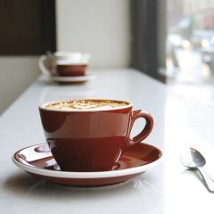 In the window at Stumptown Roasters sits a cup and saucer with a freshly made cappuccino topped with a leaf design in the foam.