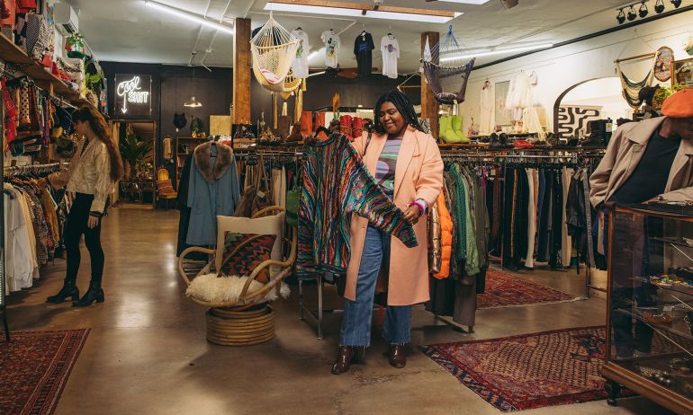 a woman looks at a sweater at Artifact PDX