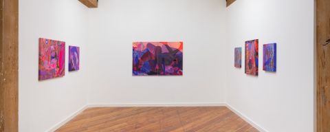 white walled interior of an art gallery with 6 paintings hanging on three sides of an open room