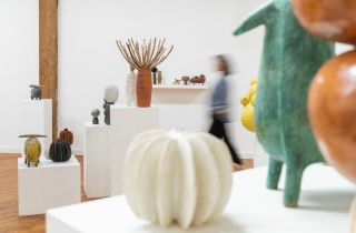 white interior of an art gallery with varied tables holding sculptures
